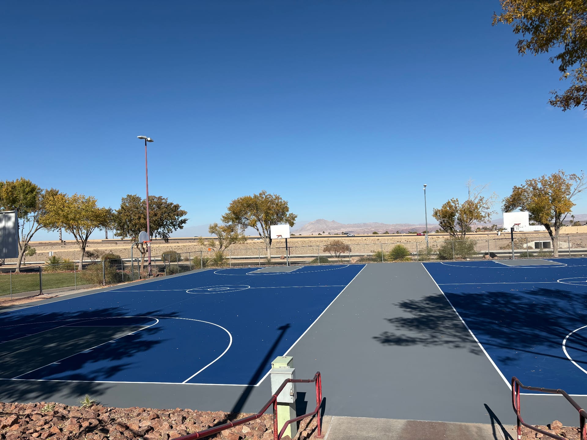 Newly resurfaced blue and grey basketball court in Henderson Nevada after crack repair and color coating