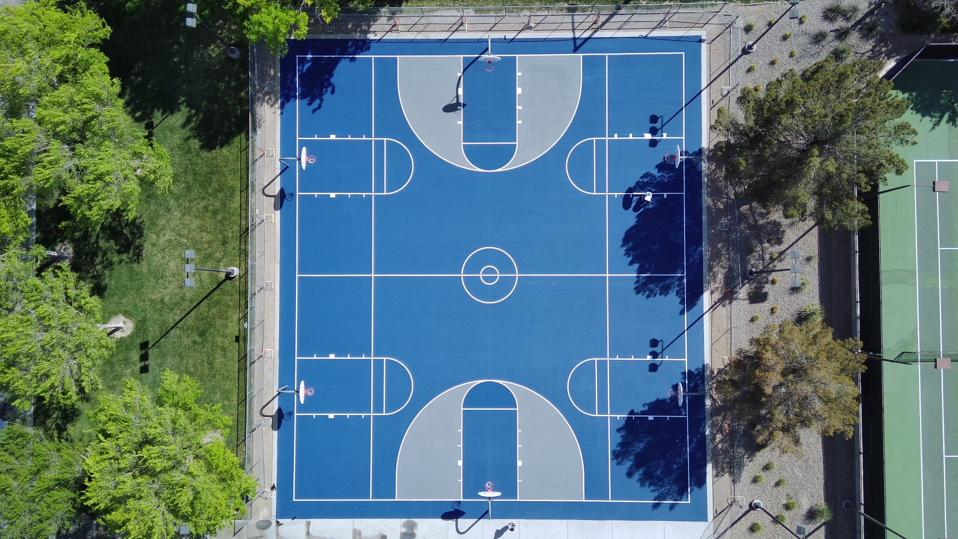 Aerial view of two blue and gray basketball courts in Summerlin, Las Vegas, featuring fresh surfacing and white court markings.