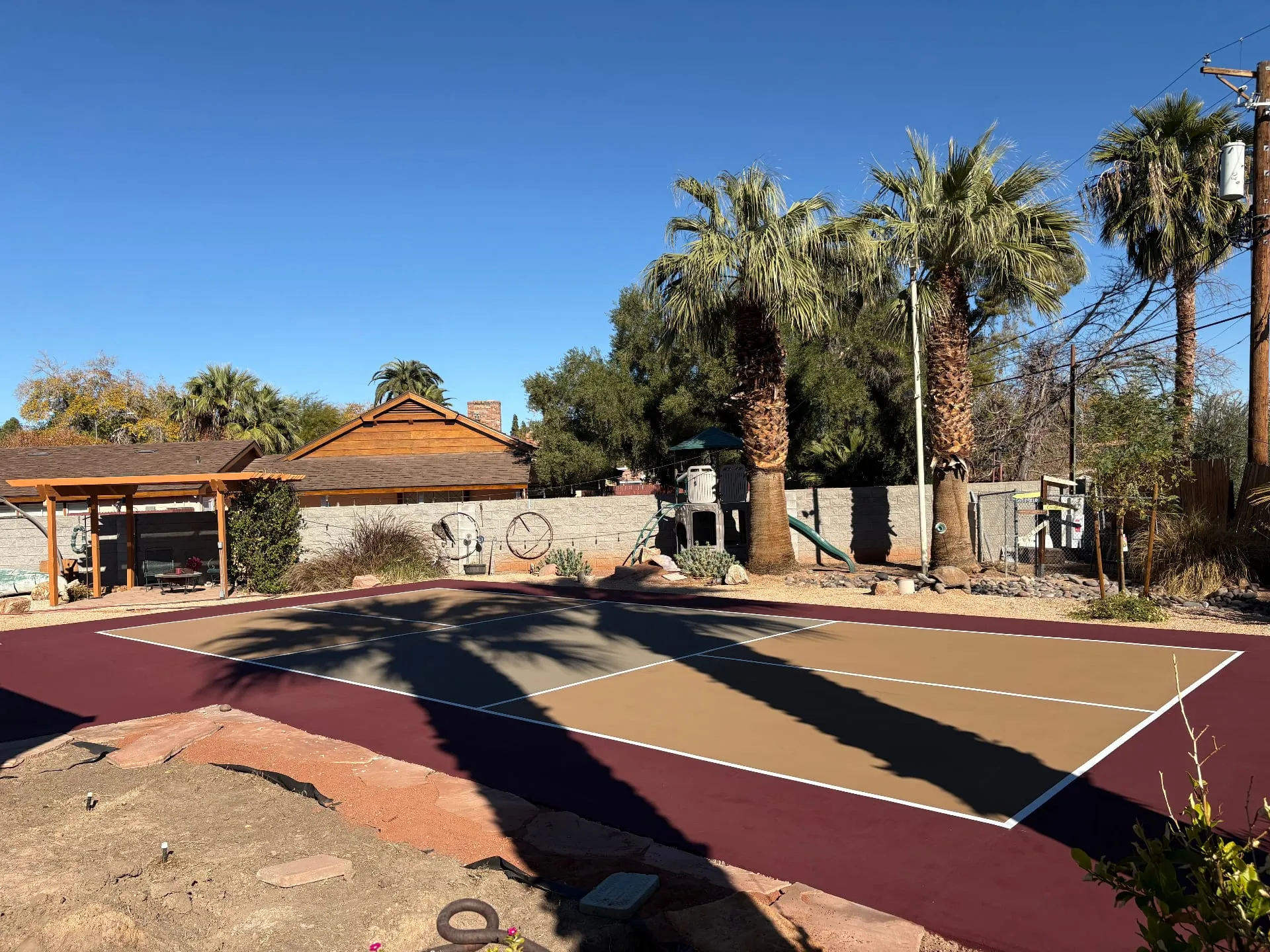 Newly resurfaced residential pickleball court with tan and burgundy color scheme in a backyard setting.