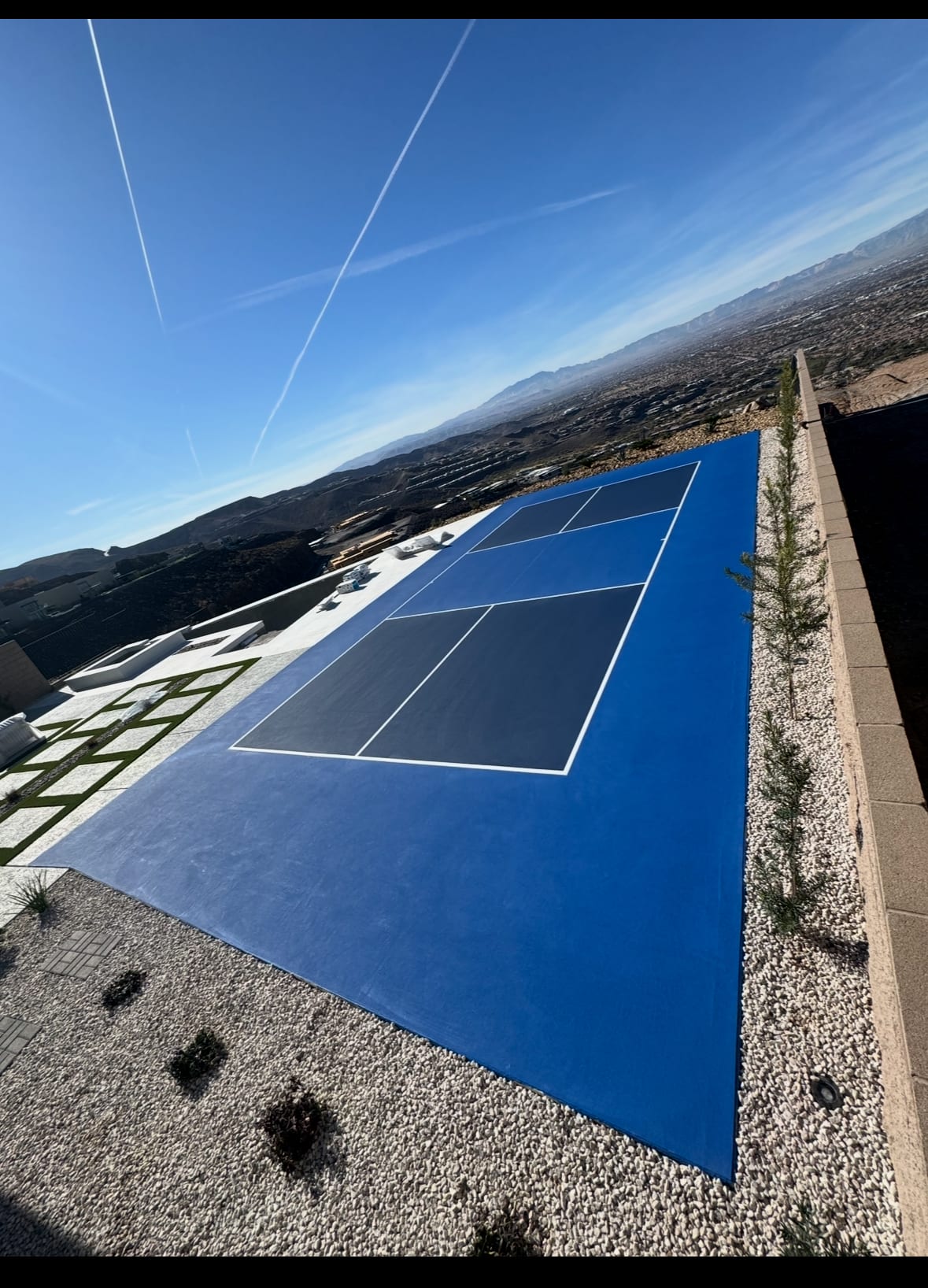 A newly surfaced blue and dark blue residential pickleball court in a Las Vegas backyard with desert mountain views.