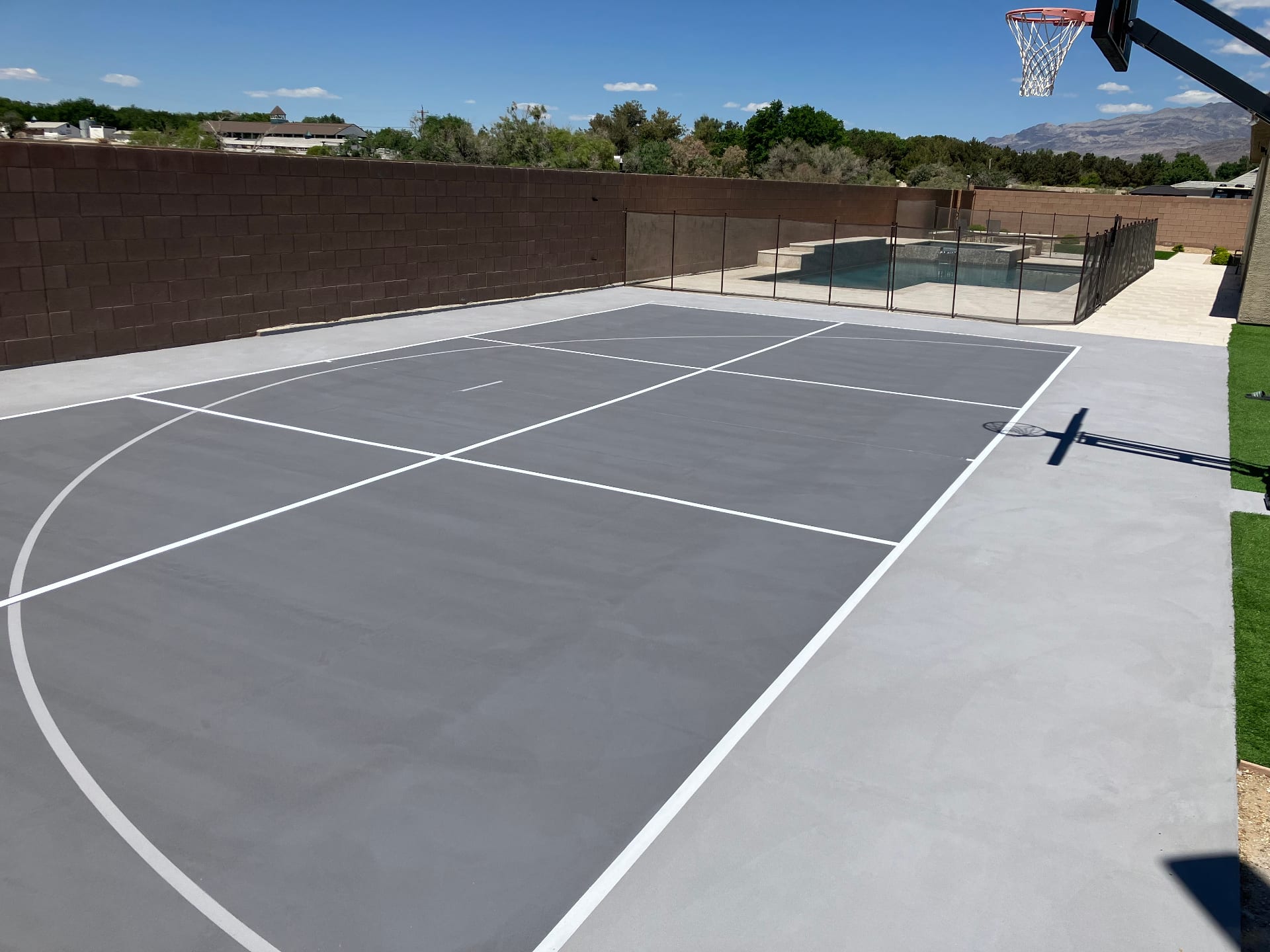 Newly resurfaced grey pickleball court in a residential backyard next to a pool in Las Vegas