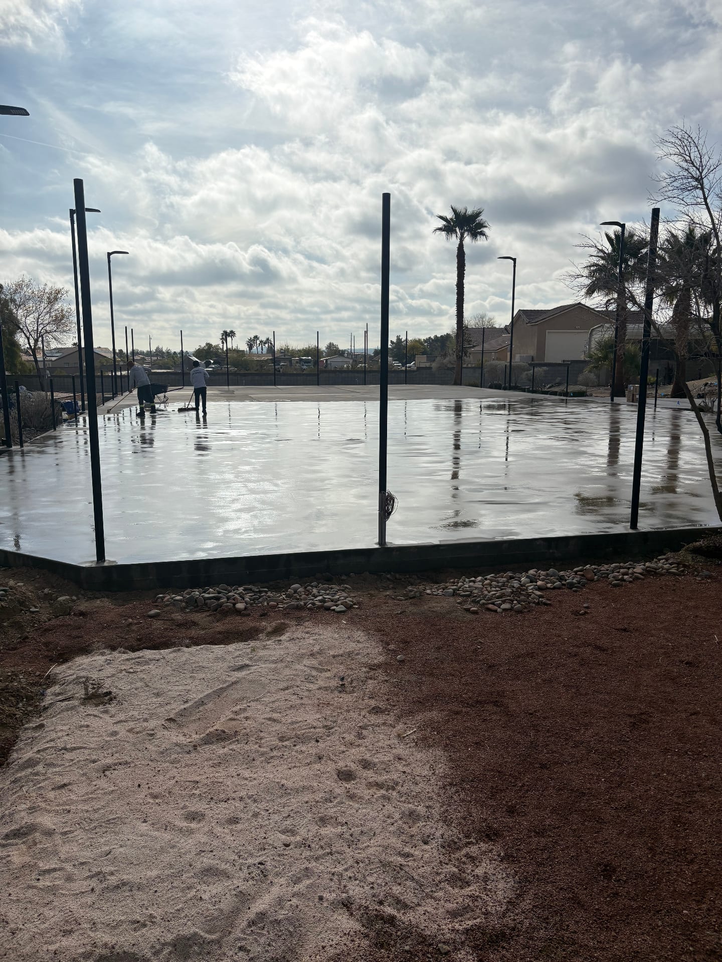 Workers finishing a fresh post-tension concrete tennis court slab in Las Vegas