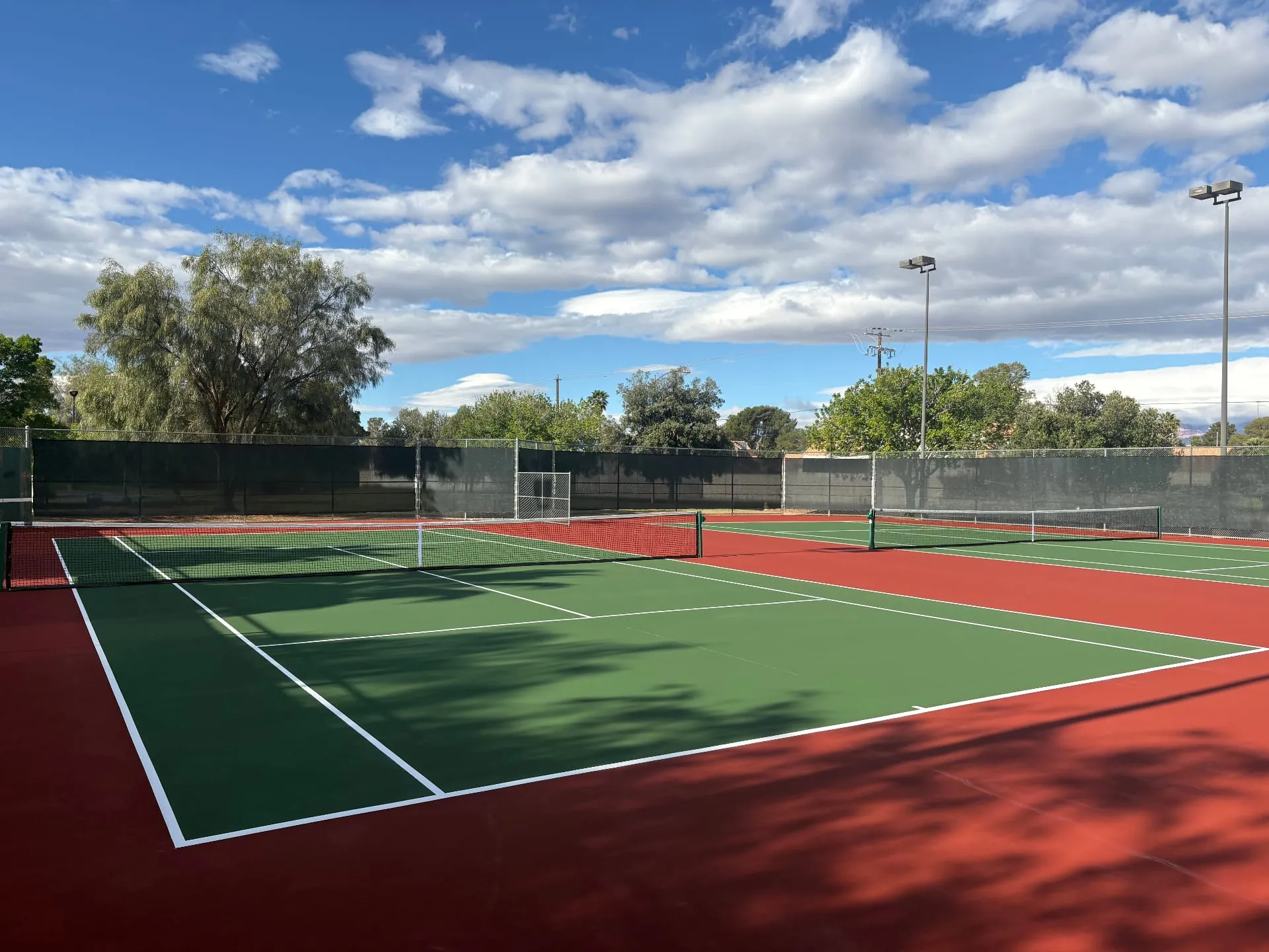 Resurfaced two-tone green and red HOA tennis courts in Las Vegas, NV with fresh white striping
