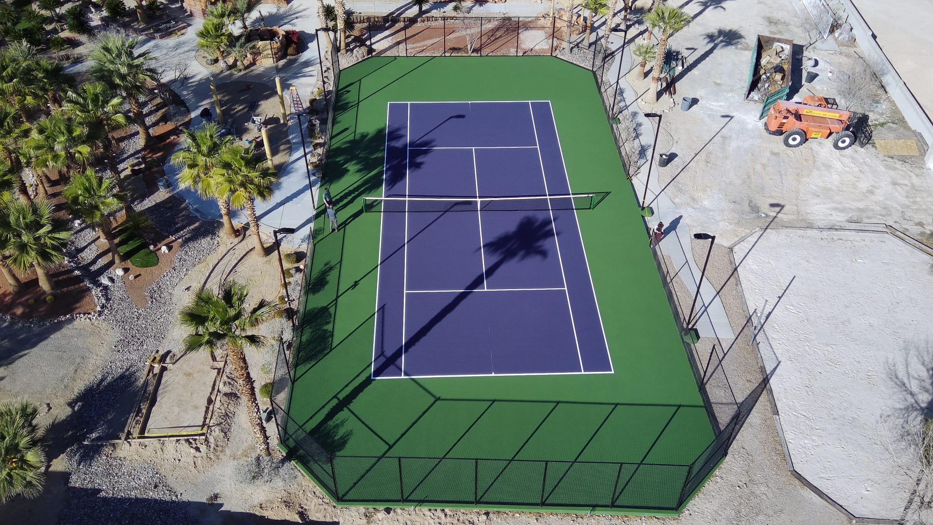 Aerial view of a newly resurfaced blue and green tennis court in Skyview, Las Vegas, featuring fresh court lines and perimeter fencing.