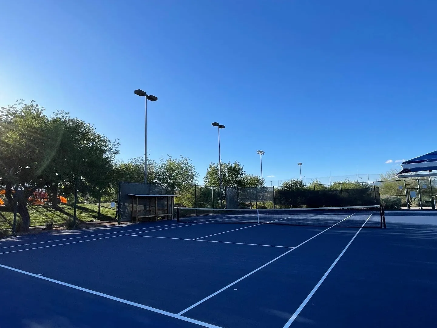 Resurfaced all-blue tennis court in Las Vegas with crisp white baselines, sidelines, and service lines