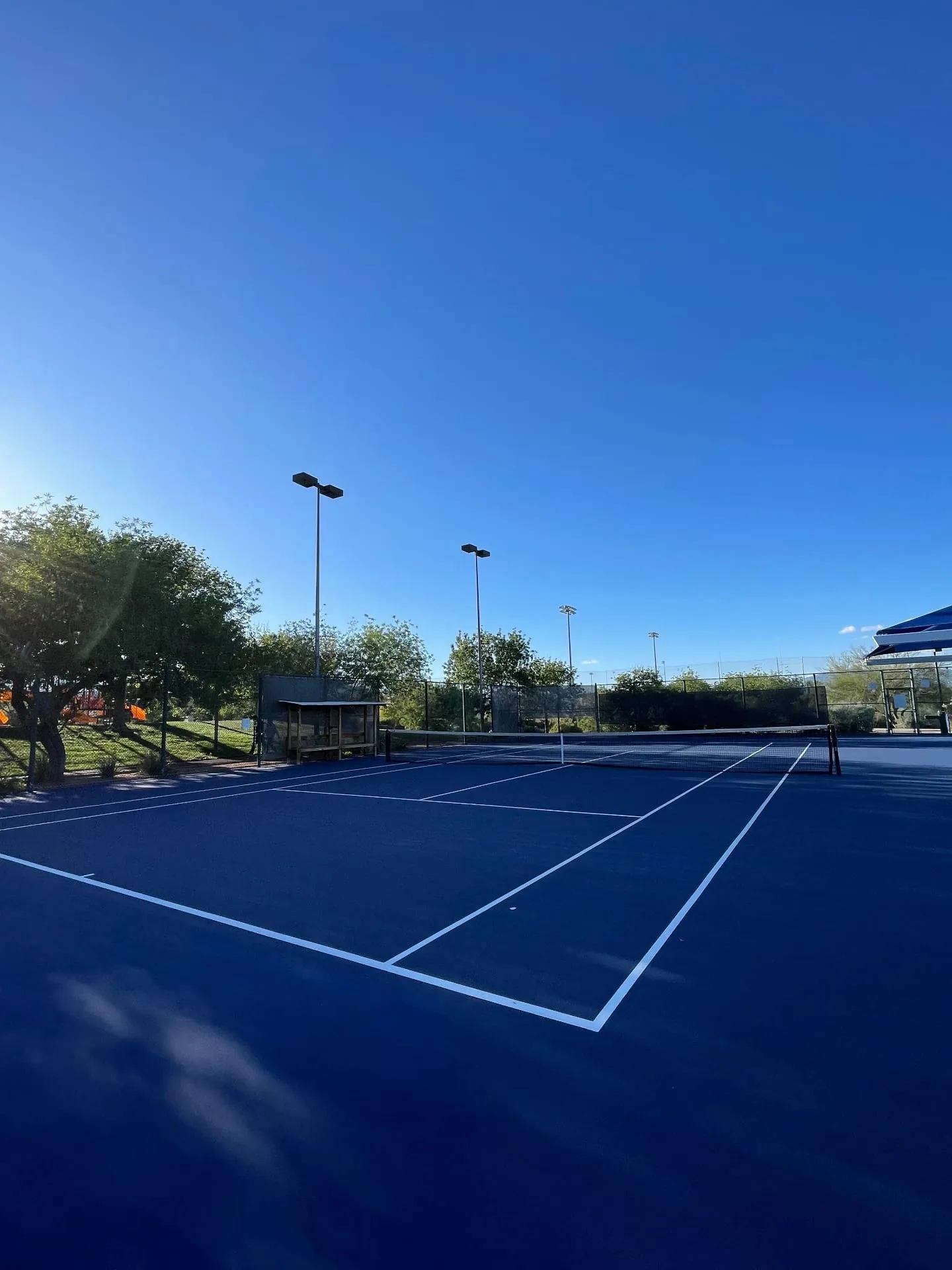 All-blue commercial tennis court resurfacing with crisp white striping and renewed color finish