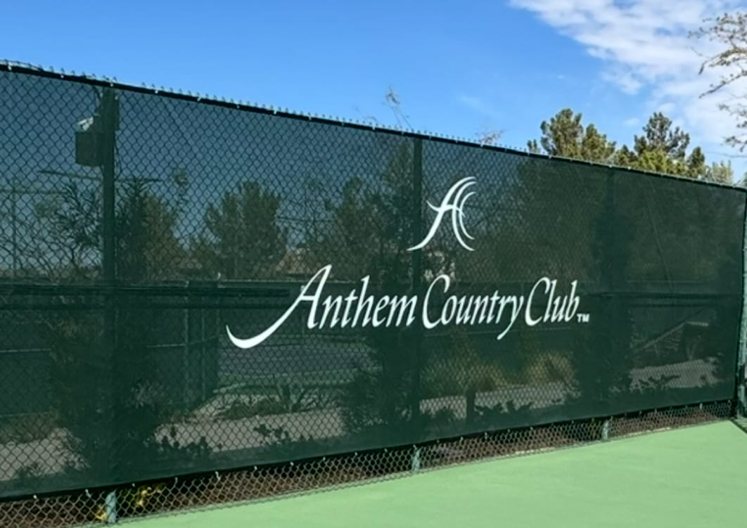 Custom green tennis court windscreen with white Anthem Country Club logo installed on chain link fence in Henderson NV